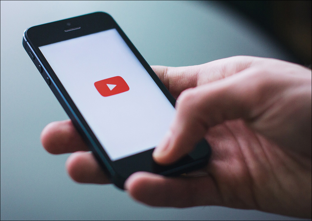 Mobile phone with YouTube video logo centered in the screen.