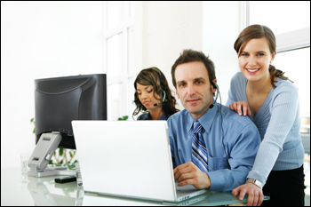 Image of business people in an office using laptops and computers.